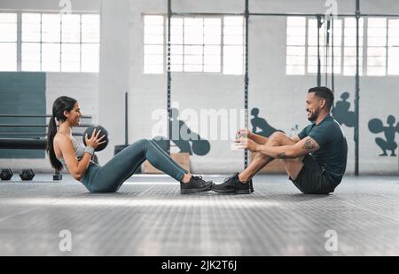 Aktive, sportliche Fitness-Paare oder Gym-Partner trainieren gemeinsam, wobei sie Kernübungen mit schweren Geräten machen. Männlicher Trainer und weibliche Athletin mit einem Stockfoto