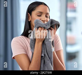 Wenn alles andere scheitert, ist Putzhaus das perfekte Gegenmittel. Eine junge Frau riecht zu Hause ein Handtuch. Stockfoto