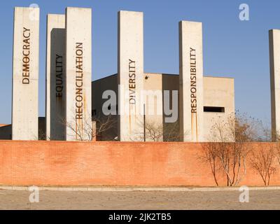 Johannesburg Südafrika - August 15 2007; Ziegelmauer mit schwarz-weißem Schild für das Apartheid Museum und Säulen mit anderen konzeptuellen Worten. Stockfoto