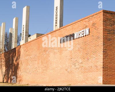 Johannesburg Südafrika - August 15 2007; Ziegelmauer mit schwarz-weißem Schild für das Apartheid Museum und Säulen mit anderen konzeptuellen Worten. Stockfoto