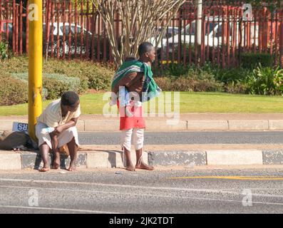 Johannesburg Südafrika - 15 2007. August; zwei junge schwarze afrikanische Frauen am Straßenrand warten mit einem Baby auf dem Rücken Stockfoto