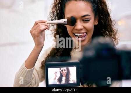 Genau so. Eine junge Frau, die sich schminkt, während sie ein Video für ihren Blog aufnimmt. Stockfoto