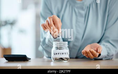 Sparsamkeit, Budget und Wirtschaftlichkeit Frau, die zu Hause Münzen in ein Glas legt. Nahaufnahme einer Frau, die ihre Ausgaben berechnet und Geld für zukünftige Investitionen spart Stockfoto