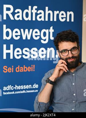 27. Juli 2022, Hessen, Frankfurt/Main: Sofrony Riedmann, die neue Geschäftsführerin des ADFC Hessen, sitzt in seinem Büro vor einem Display mit den Worten „Radfahren bewegt Hessen“. Im Kampf um eine Verkehrskehrtwende will der ADFC auch ungewöhnliche Allianzen schmieden, um den Druck auf die Politik zu erhöhen. Riedmann leitet den Verein seit dem 1. Juli 2022 als Geschäftsführer. (An dpa 'Neuer ADFC-Geschäftsführer gibt Radwegen in Hessen eine schlechte Note') Foto: Arne Dedert/dpa Stockfoto