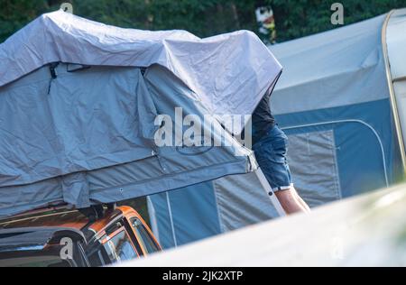 Karlshagen, Deutschland. 29.. Juli 2022. Ein Mann richtet auf dem Campingplatz Dünencamp auf der Insel Usedom ein Dachzelt auf. Quelle: Stefan Sauer/dpa/Alamy Live News Stockfoto