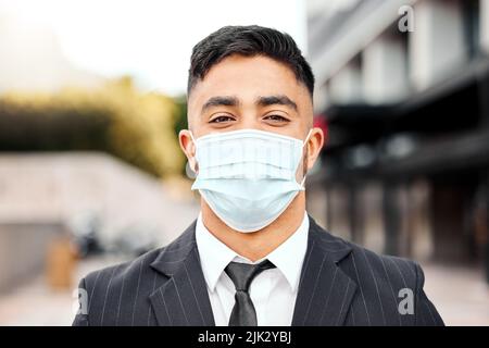 Seien Sie sicher, wenn Sie draußen sind. Ein junger Geschäftsmann trägt eine schützende Gesichtsmaske. Stockfoto