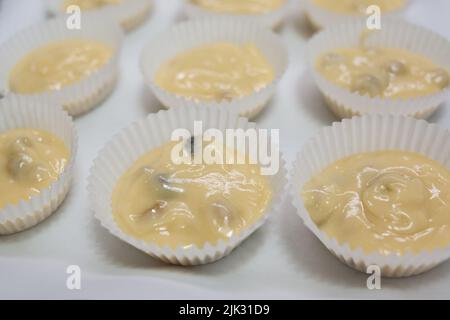 Papierkisten gefüllt mit Muffinteig Stockfoto