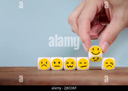 Handwechsel mit Lächeln Emoticon Symbole Gesicht auf Holzwürfel , Hand flipping unglücklich Drehen zu glücklichen Symbol Stockfoto