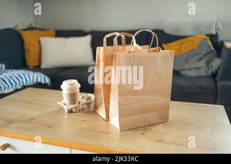 Lieferkonzept. Papiertüten und Kaffee auf einem Tisch. Kontaktloser Lieferservice, Lebensmittelmitnahme, Sperrung, Quarantäne, Pandemie, Coronavirus Stockfoto