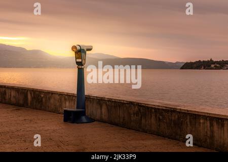 Sonnenaufgang über dem Gardasee, Ferngläser warten auf Touristen, um einen Blick über den See zu werfen Stockfoto