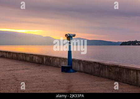 Sonnenaufgang über dem Gardasee, Ferngläser warten auf Touristen, um einen Blick über den See zu werfen Stockfoto