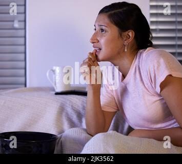 Die Spannung tötet mich. Eine junge Frau, die zu Hause fernsehen schaut. Stockfoto