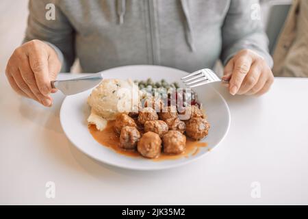 Frau Hände essen Hackfleischschnitzel mit Kartoffelpüree auf weißem Teller im Stadtcafe Stockfoto