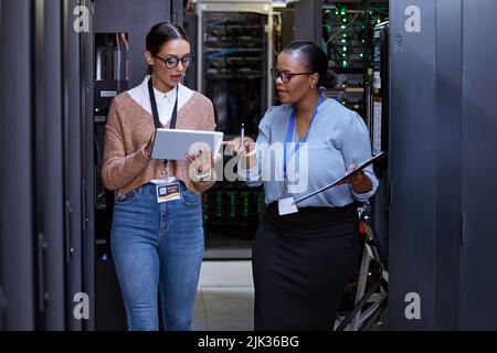 Überprüfen wir die Konnektivität. Zwei attraktive junge Computerprogrammiererinnen arbeiten in einem Serverraum zusammen. Stockfoto