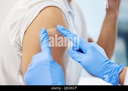 Eine nicht erkennbare Ärztin, die ihrem Patienten ein Pfand gab, nachdem sie ihm den Covid-Impfstoff gegeben hatte. Stockfoto