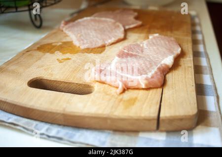 Rohes Schweinelende-Koteletts auf einem Brett Stockfoto