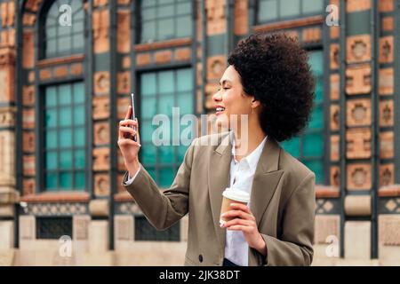 Frau lächelt glücklich, einen Videoanruf im Freien zu tätigen Stockfoto
