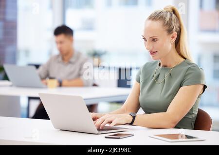 Diese E-Mail erfordert meine sofortige Aufmerksamkeit. Eine attraktive junge Geschäftsfrau, die im Büro sitzt und ihren Laptop benutzt. Stockfoto