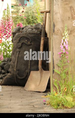 Säcke Kohle und eine Schaufel durch einen Gartenschuppen. Stockfoto