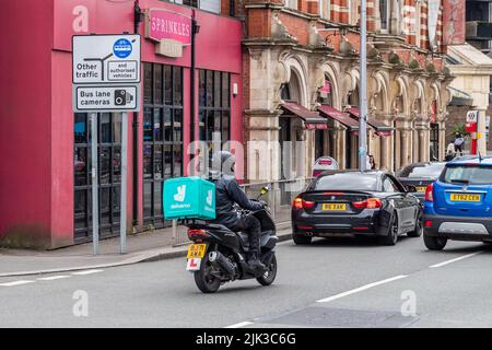 Deliveroo Delivery Rider auf einem Roller, der Lebensmittel in Coventry, West Midlands, Großbritannien liefert. Stockfoto