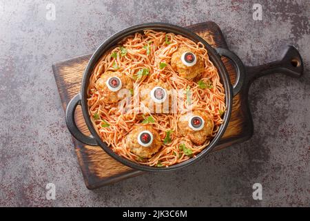 halloween Spaghetti mit Tomatensauce und Fleischbällchen mit Augen in einer Bratpfanne auf dem Tisch aus nächster Nähe. Horizontale Draufsicht von oben Stockfoto