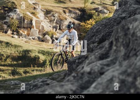 Professioneller Radsportler mit Mountainbike auf dem Trail im felsigen Gelände Stockfoto