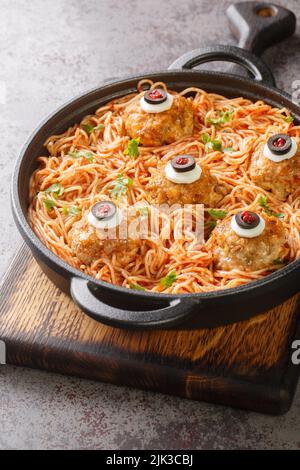 Pasta dekoriert mit Fleischbällchen Augen Nahaufnahme in den Teller auf dem Tisch Menü an Halloween. Vertikal Stockfoto