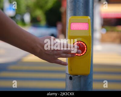 Nahaufnahme einer Signaltaste für den Fußgängerüberweg, die an einer Fußgängerüberfahrt aufgenommen wurde. Handtaste zum Überkreuzen Stockfoto