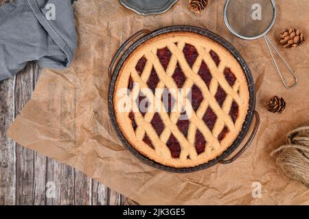 Draufsicht auf hausgemachten Kuchen namens 'Linzer Torte', ein traditionelles österreichisches Shortcake-Gebäck mit Obstkonserven und gemahlenen Nüssen mit Gitterdessig Stockfoto