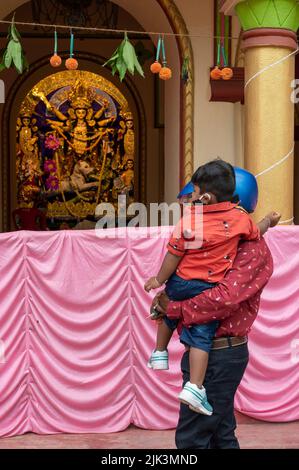 Howrah, Indien -26.. Oktober 2020 : Vater mit Helm auf, zeigt Göttin Durga seinem Kind, Durga im Alter dekoriert Haus. Durga Puja. Stockfoto