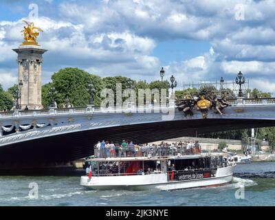 Paris, Frankreich - 15. Juni 2019: Touristenboot, das während des sonnigen Sommertages unter der Brücke Alexander III (Pont Alexandre III) fährt Stockfoto