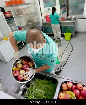 (220730) -- PEKING, 30. Juli 2022 (Xinhua) -- Wang Zheng bereitet das Frühstück für Schimpansen im Pekinger Zoo in Peking, der Hauptstadt Chinas, vor, 14. Juli 2022. Wang Zheng arbeitet seit 17 Jahren im Gorilla-Haus des Pekinger Zoos. Er kümmert sich um alle Aspekte der hier lebenden Tiere. Als Züchter muss Wang die psychologischen Aktivitäten, das Temperament und die Verhaltensmuster der Tiere lernen und verstehen, um eine bessere Zucht zu erreichen. Der unvergesslichste Moment für Wang über die Jahre war, als Nan Nan, ein künstlich erzogener Schimpanse, 2021 ein weibliches Junge zur Welt brachte. Es war das zweite Mal Stockfoto