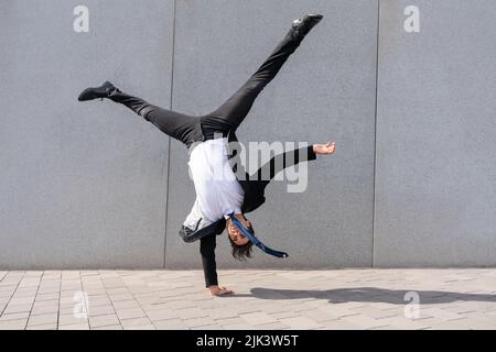 Glücklich und gut aussehend erwachsenen Geschäftsmann in eleganten Anzug tun akrobatische Trick bewegt sich in der Stadt, alternative Konzept für Business-Werbung mit Stockfoto