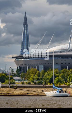 Russland, St. Petersburg, 29. Juli 2022: Das neue Gebäude des Fußballstadions Gazprom Arena, Segel-und Motorboote sind in der Nähe der Böschung, die vertäut Stockfoto