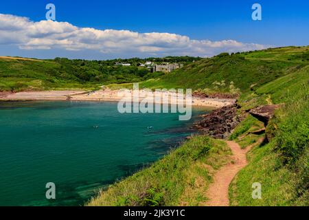 Der Pembrokeshire Coast Path im Nationalpark umrundet die Manorbier Bay mit ihren roten Sandsteinfelsen und dem Sandstrand, Wales, Großbritannien Stockfoto