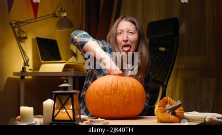 Ich bereite Kürbis für Halloween vor. Eingeweide und Samen herausziehen und sich davon erzürnen lassen. Eine Frau, die zu Hause halloween Jack O Lantern Kürbis für ihre Familie schnitzt. Stockfoto