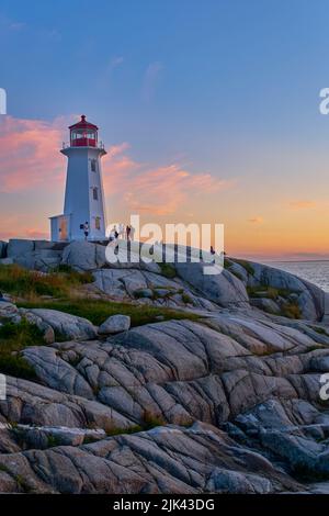 Touristen treffen sich auf dem berühmten Peggy's Cove Leuchtturm und sehen den atemberaubenden Sonnenuntergang. Stockfoto