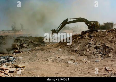 (LOGISTIKSTÜTZGEBIET ANACONDA, Balad, Irak) - Soldaten des Bataillons des Kampfingenieurs von 84. verwenden einen Bulldozer und Bagger, um Müll und andere brennbare Gegenstände in der Brenngrube auf der Deponie hier zu manualieren. Der Bulldozer wird hauptsächlich dazu verwendet, den Abfall ständig zu verbrennen, und der Bagger wird Schmutz über die Rinnen schieben, um das Land in Zukunft nutzbar zu machen. Stockfoto