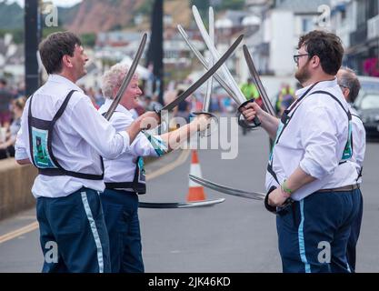 Sidmouth, 30.. Juli 2022 Saber Dance - Morris Tänzer treffen auf der Sidmouth Esplanade auf Schwerter, während die Folk Week beginnt. Tony Charnock/Alamy Live News Stockfoto