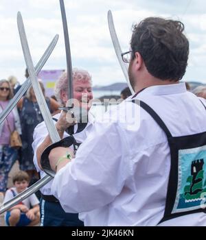 Sidmouth, 30.. Juli 2022 Saber Dance - Morris Tänzer treffen auf der Sidmouth Esplanade auf Schwerter, während die Folk Week beginnt. Tony Charnock/Alamy Live News Stockfoto