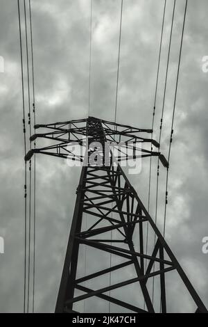 Power Line Pylon vor dem Hintergrund des dunklen bewölkten Himmels Stockfoto