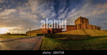 Ein Panoramablick auf Schloss Carlisle mit dem Turm von De Ireby, dem Bergturm und der Brücke über den äußeren Burggraben bei Sonnenuntergang. Stockfoto