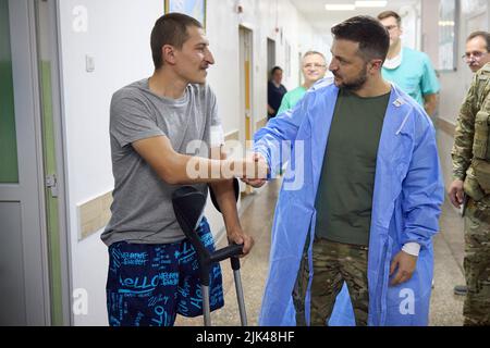 Odessa, Ukraine. 29.. Juli 2022. Der ukrainische Präsident Wolodymyr Zelenskyy, rechts, schüttelt sich die Hände mit einem Soldaten, der während eines Besuchs mit verwundeten Kriegern während eines Krankenhausaufenthalts, bei dem ukrainische Verteidiger am 29. Juli 2022 in Odessa, Ukraine, behandelt wurden, sein Bein verlor. Kredit: Ukrainisches Presidential Press Office/Ukraine Presidency/Alamy Live News Stockfoto