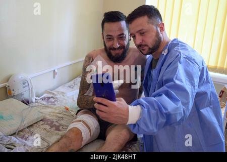 Odessa, Ukraine. 29.. Juli 2022. Der ukrainische Präsident Wolodymyr Zelenskyy, rechts, macht ein Selfie mit einem Soldaten, der während eines Besuchs mit verwundeten Kriegern während eines Krankenhausaufenthalts verletzt wurde, der ukrainische Verteidiger am 29. Juli 2022 in Odessa, Ukraine, behandelt. Kredit: Ukrainisches Presidential Press Office/Ukraine Presidency/Alamy Live News Stockfoto