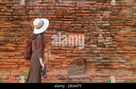 Weibliche Reisende beim Spaziergang entlang der alten Außenmauer des Archäologischen Komplexes Wat Phra Si Sanphet, Ayutthaya Historical Park, Thailand Stockfoto