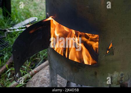Feuer in einem Metallofen. Kochen im Freien. Stockfoto
