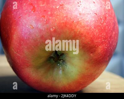 Ein großer roter Apfel auf einer hölzernen Oberfläche, eine Nahaufnahme. Stockfoto