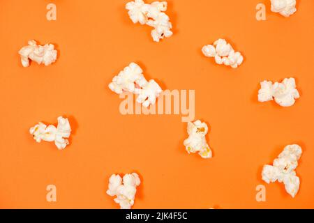 Popcorn auf orangefarbenem Hintergrund, Nahaufnahme von oben. Stockfoto