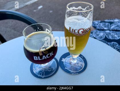 Zwei Gläser Bier, Lacorne-Lager und Lacorne-Schwarz auf Biermatten, runder französischer Café-Tisch auf dem Bürgersteig Stockfoto