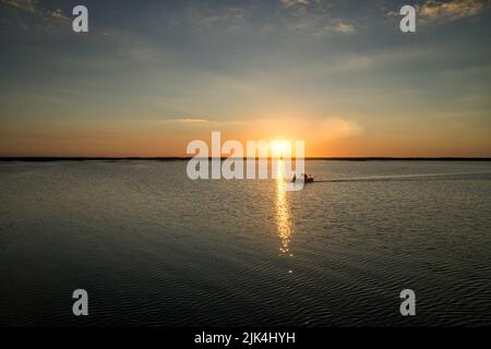 Bei Sonnenuntergang kehren die Fischer vom Fischfang am Lebsko-See zurück. Wolkenloser Himmel, Sommer, Licht wird im Wasser reflektiert. Pommern, Polen, Europa. Stockfoto